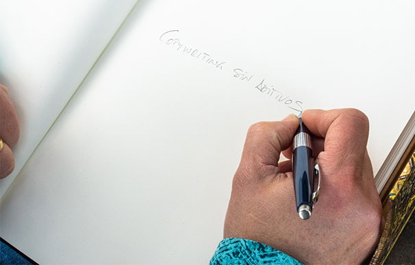 Mano de Vanesa Capó copywriter freelance escribiendo “Copywriting sin aditivos” sobre un cuaderno.